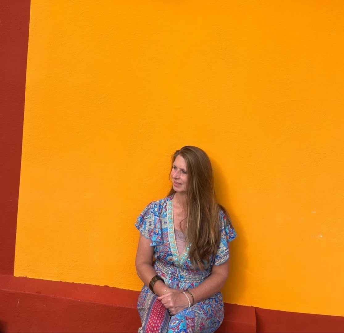 Séverine assise devant un mur ocre, vêtue d’une robe à motifs